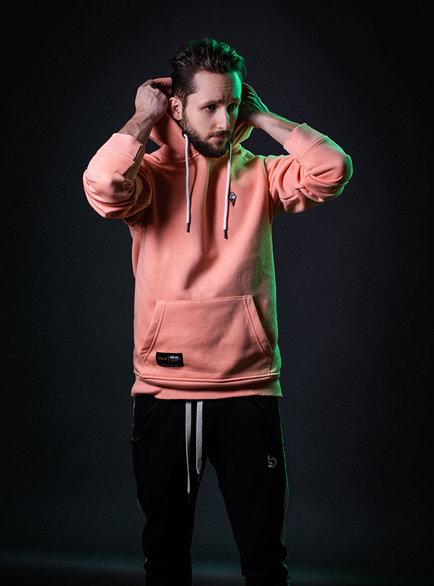 Mann in rosa Hoodie und schwarzer Hose posiert