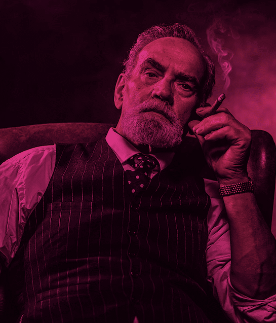 Älterer Herr raucht Zigarre im Sessel.